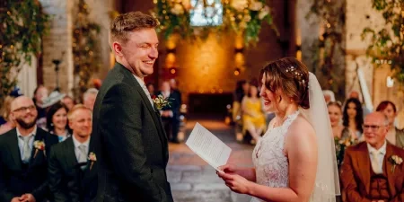 A photo of a bride delivering her vows to the groom. They are both laughing and enjoying the moment.