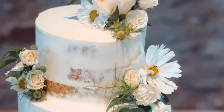 A picture of a wedding cake decorated with butter cream and white flowers.